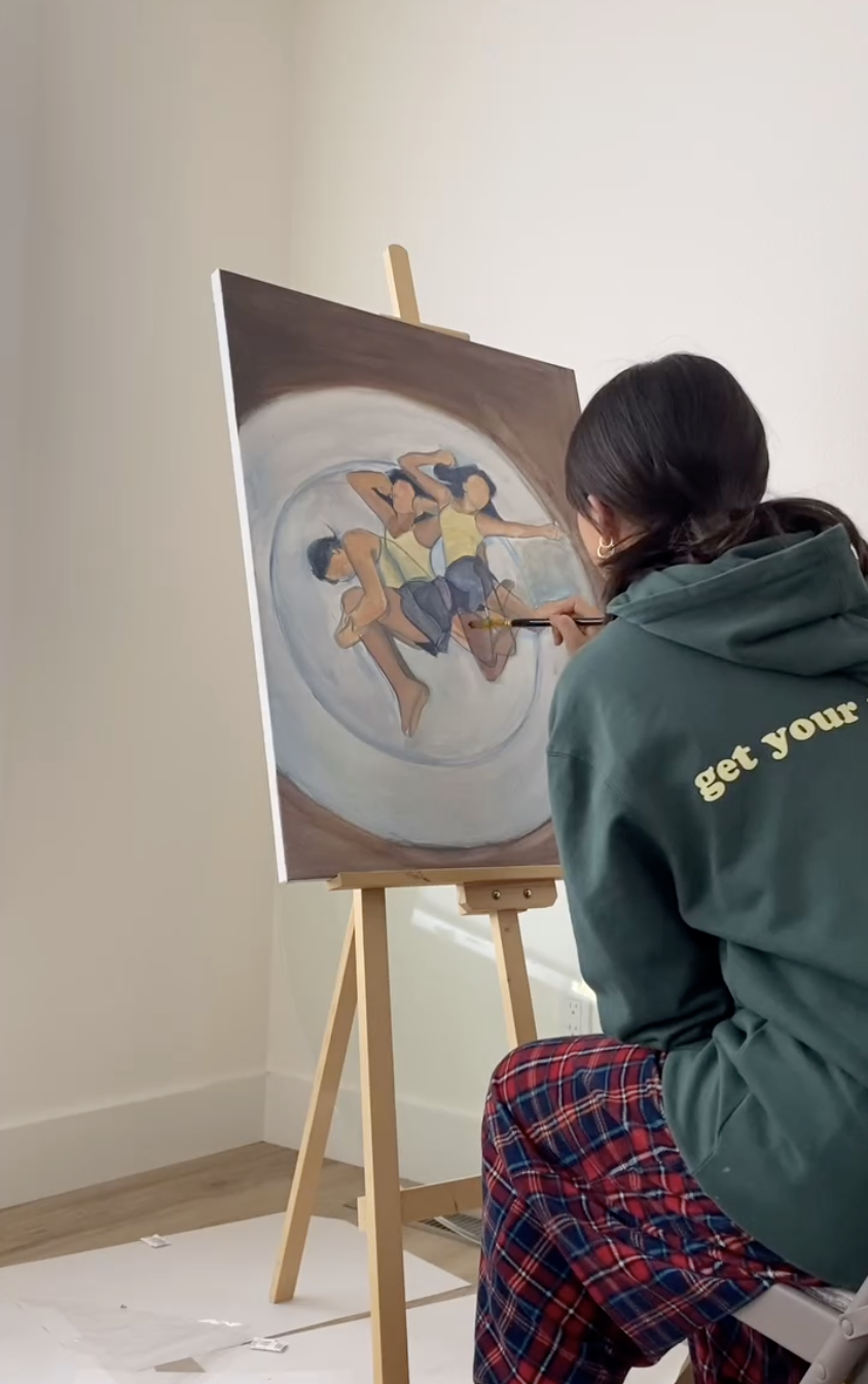Joyce painting a circular figure composition on an easel