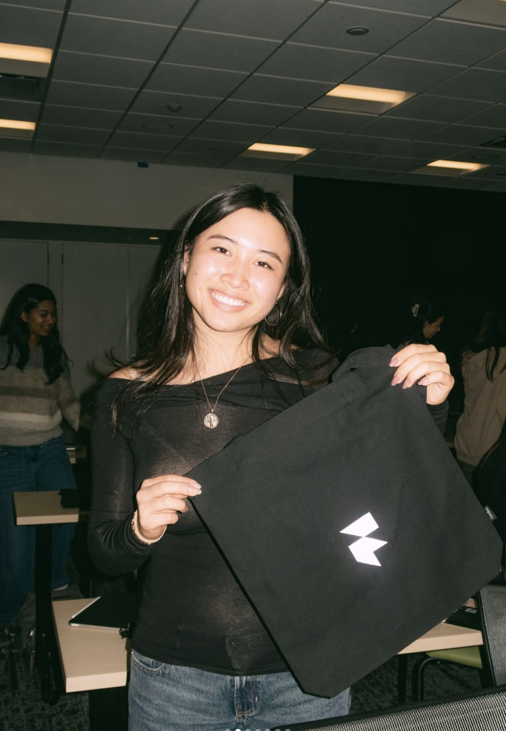 Joyce smiling and holding a black Framer tote bag